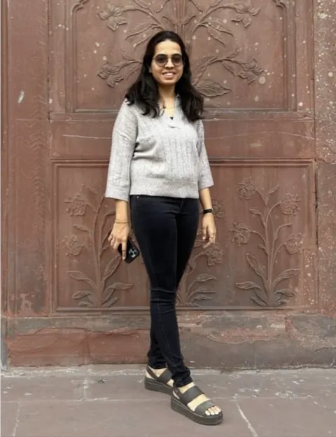 Haripriya in front of a carved red sandstone wall