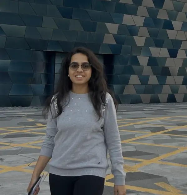 Haripriya walking in front of a geometric tiled facade