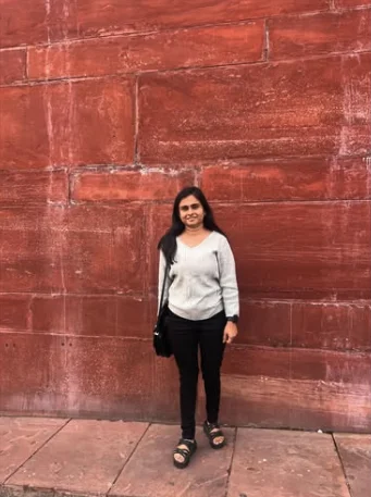 Sachi standing in front of a red sandstone wall